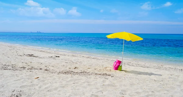 Deštník a taška na tropické pláži — Stock fotografie