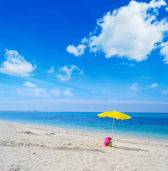 Зонтик и сумка на тропическом пляже — стоковое фото