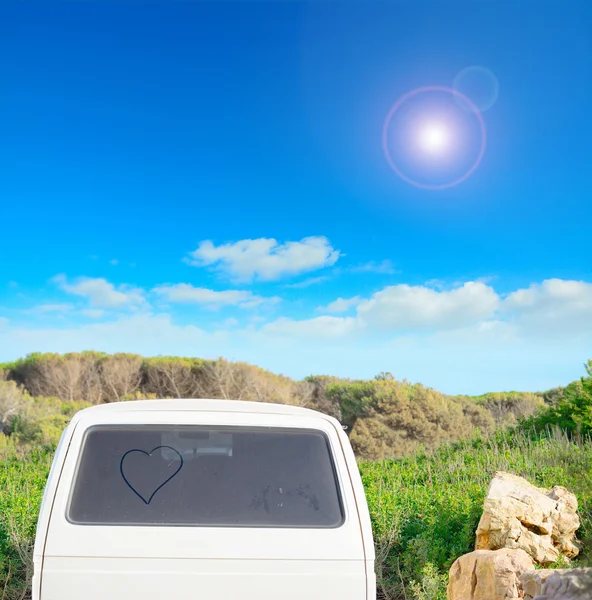 Corazón dibujado en una ventana trasera sucia en el verano — Foto de Stock