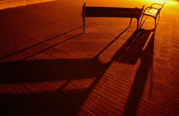 Bänke und ihre Schatten auf einer gepflasterten Straße — Stockfoto