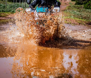 Kahverengi bir su birikintisinde gezinen macera motosikleti