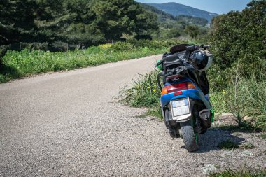 Motosiklet boş bir kır yolunun kenarına park edilmiş.