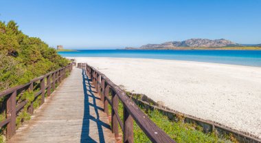La Pelosa sahiline giden tahta kaldırım berrak mavi bir gökyüzünün altında beyaz kum ve turkuaz deniz ile İtalya 'nın Sardunya şehrinde..