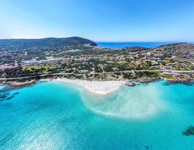 Stintino 'daki La Pelosa sahilinin havadan görünüşü, kıyı şeridinin arkasındaki tepe, turkuaz Akdeniz suyu ve Sardunya' nın kuzey kıyısı boyunca uzanan parlak mavi gökyüzü..