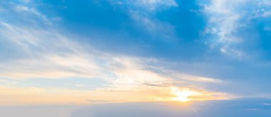 Güneş batan gökyüzü, çerçevenin alt üçte birinde, yumuşak bulutlar ve açık gökyüzü ile çevrili. Kompozisyon, temiz ve dengeli bir atmosferik arkaplan ve sıcak ışık sunuyor..