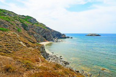 Sardinya bir bulutlu gökyüzü altında kayalık sahil