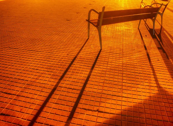 Benches and their shadows on a paved street — Stock Photo, Image