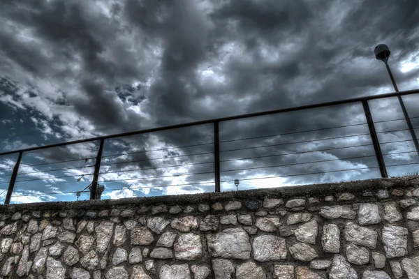 Muro de piedra bajo un cielo gris dramático — Foto de Stock