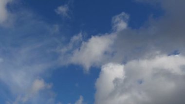 Kümülüs bulutları mavi gökyüzünde alçaktan uçuyor.