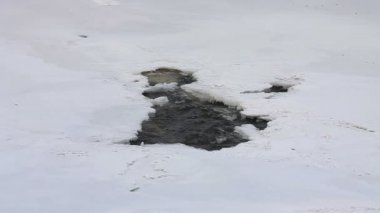 Donmuş kış nehrinde karla kaplı bir buz deliği