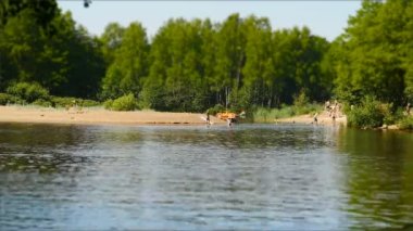 İnsanlar dinleniyor, kayıkla geziyor, sıcak bir yaz gününde nehirde yüzüyor, zaman geçiyor.