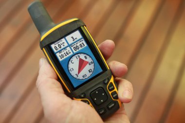 Bir adamın elinde bir turist GPS navigatörünün ekranında pusula