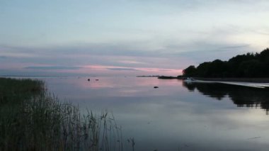 Resimli bir gölde sakin bir akşam. Bir motorlu tekne yükselen dalgalarda yüzüyor.