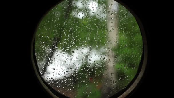 Lluvia en la portilla redonda mirando hacia fuera — Vídeo de stock