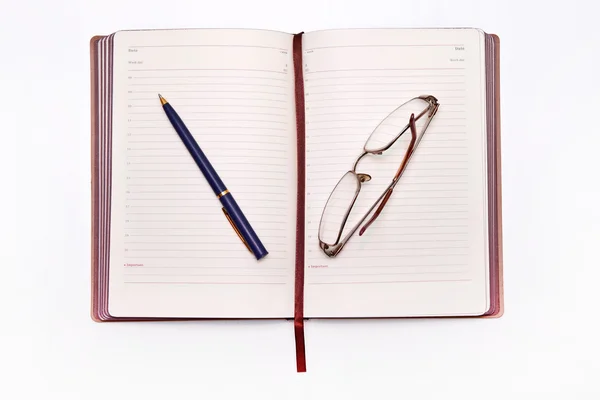 Jasné, zápisník, sklenice a knihy na stole — Stock fotografie