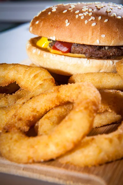 Delicious freshly prepared burger and onion rings on the table. Fast food