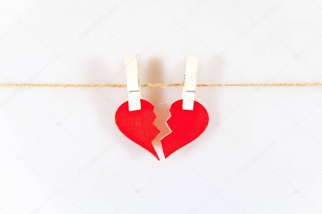 Broken heart on two clothespins. Failed love. White background