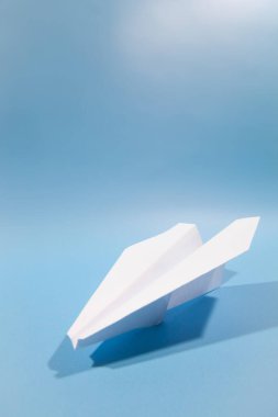 Düz beyaz kağıt uçak ve mavi arka plan. Seyahat kavramı