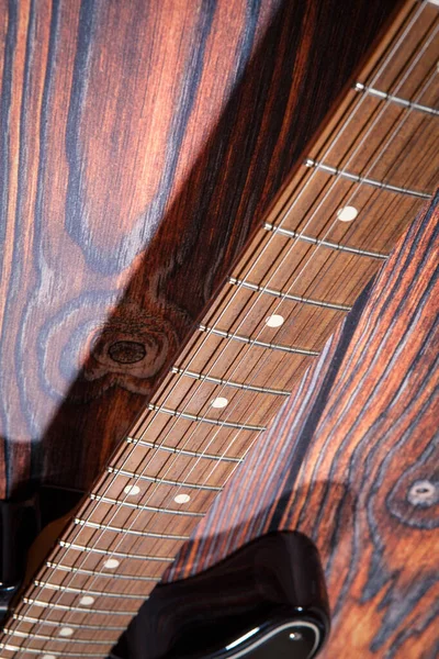 Electric guitar body close-up on the wooden board. Detail of black electric guitar