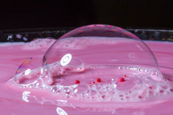 Splash of milk drop in pink color under the buble. — Stock Photo, Image
