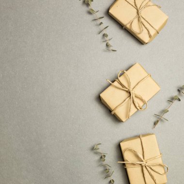 Gri arka planda okaliptüs yapraklı hediye kutuları. düz alan, üst görünüm, kopyala boşluk