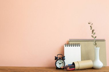 Defter, saat, okaliptüs vazosu olan kalemler. pembe arka plan. Çalışma ve öğrenim yeri