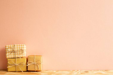 Tahta masadaki sarı hediye kutuları. mercan pembe arkaplan