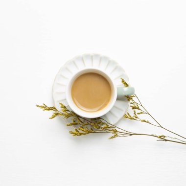 Beyaz arka planda kuru bitki olan bir fincan kahve. Üst görünüm, boşluk kopyala