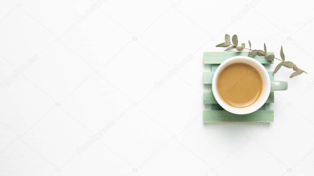 Cup of coffee with dry eucalyptus on white background. top view, copy space