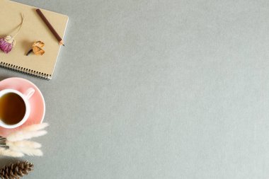 Not defteri ve bir fincan siyah çay ve gri arka planda kuru bitki. Üst görünüm, boşluk kopyala