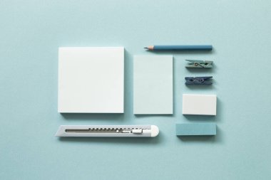 Mavi kırtasiye. Not defteri, kesici, renkli kalem, ataç, mavi arka planda silgi. Düz konum, üst görünüm, kopyalama alanı. Çalışma ve öğrenim yeri