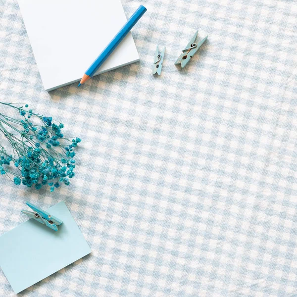 Work and study place. Notepad, colored pencil, clip on blue check pattern fabric background. flat lay, top view, copy space