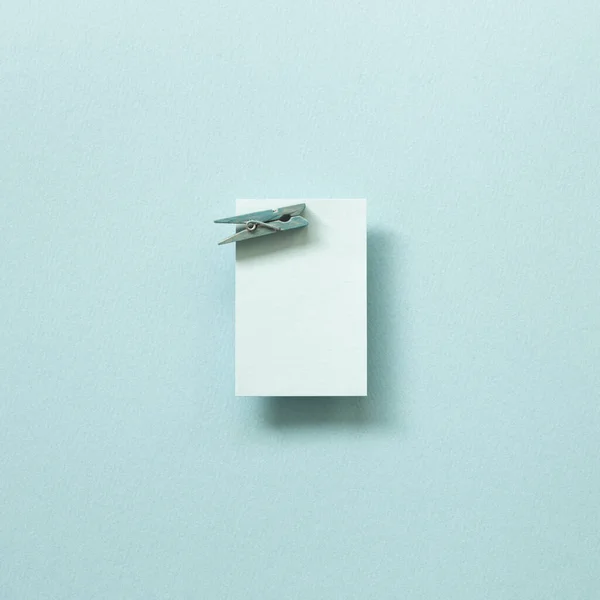 Blue memo pad with wooden clip on blue background. top view, copy space