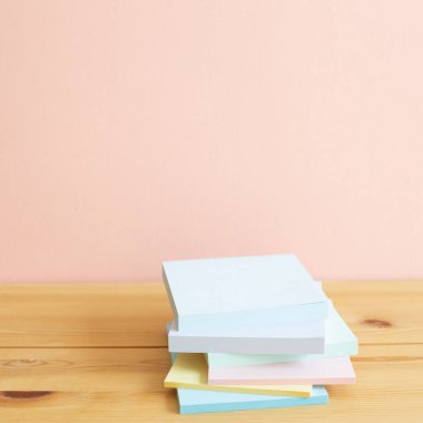 Renkli not defterleri, ahşap masadaki yapışkan notlar. Pembe arkaplan, kopyalama alanı. Çalışma ve öğrenim yeri