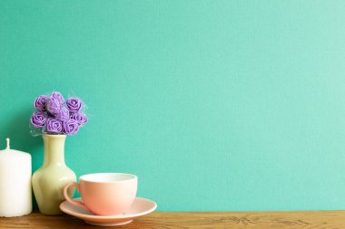 Çiçekli pembe kahve fincanı ve ahşap masa üzerinde mum. yeşil arkaplan