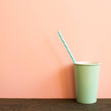 Tahta masada saman içen yeşil kupa. pembe arkaplan