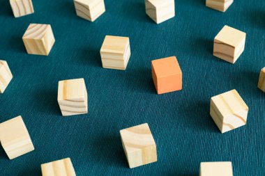 Group of wooden blocks and one different color block on blue background. Different opinion, direction, idea, innovation concept