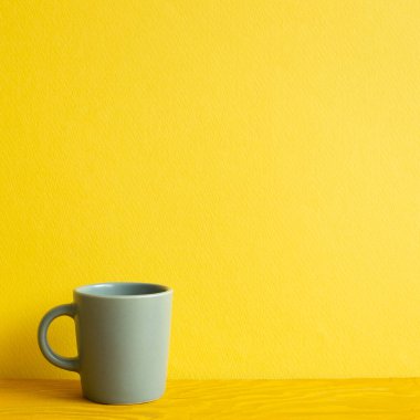 Gri bardak ahşap masada. sarı arkaplan