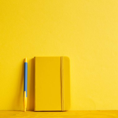 Sarı defter ve kalem ahşap masada. sarı arkaplan