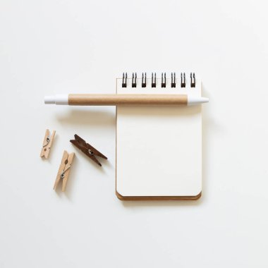 Boş bir defter, beyaz arka planda tahta bir ataç. Üst görünüm, boşluk kopyala