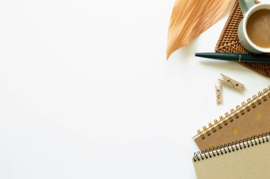 Bir fincan kahve, defter, tahta ataç, beyaz arka planda kalem. Çalışma ve öğrenim yeri. düz alan, üst görünüm, kopyala boşluk