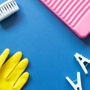 Çamaşır tahtası, mandallar, fırça, mavi arka planda lastik eldivenler. Çamaşır ve temizlik konsepti. Üst görünüm, boşluk kopyala