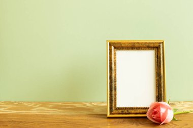 Ahşap masada gül çiçekli boş fotoğraf çerçevesi. yeşil arkaplan