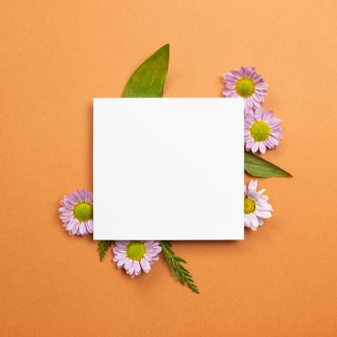 Turuncu arka planda pembe çiçekli beyaz not defteri. düz alan, üst görünüm, kopyala boşluk