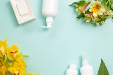 Banyo beyaz şişeleri ve mavi arka planda sabun. Düz konum, üst görünüm, kopyalama alanı. Cilt bakımı ve kaplıca kavramı