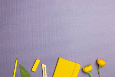 Sarı kırtasiye. Not defteri, kesici, renkli kalem, mor arka planda çiçek. düz alan, üst görünüm, kopyala boşluk