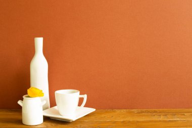 Ahşap masada vazo vazosu olan beyaz kahve fincanı. kahverengi arkaplan