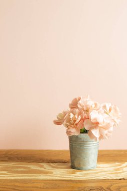 Vazo dolusu pastel pembe karanfil. Ahşap masa üzerinde çiçekler.