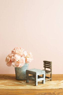 Okul masası ve pembe karanfil çiçekli boş sandalye.