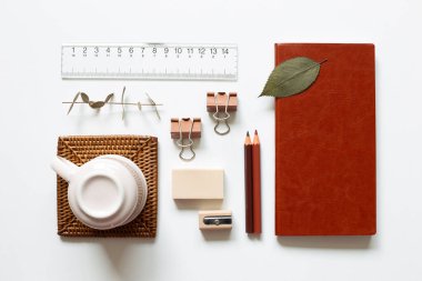 Ofis masası Defter, renkli kalem, kalem açacağı, silgi, ataç, bardak, beyaz arka planda cetvel. Üst görünüm, boşluk kopyala